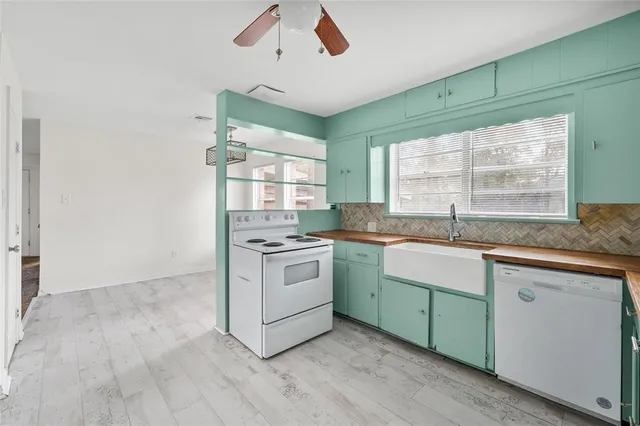 a kitchen with granite countertop a sink cabinets stainless steel appliances and a large window