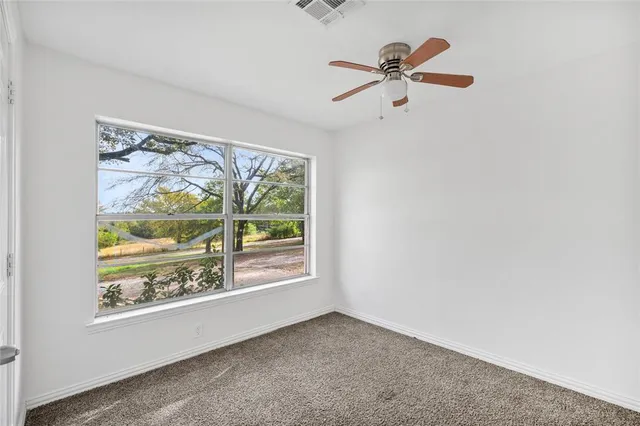 an empty room with ceiling fan and window