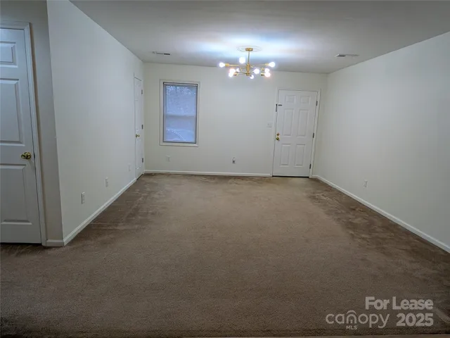 en empty room with windows and chandelier fan