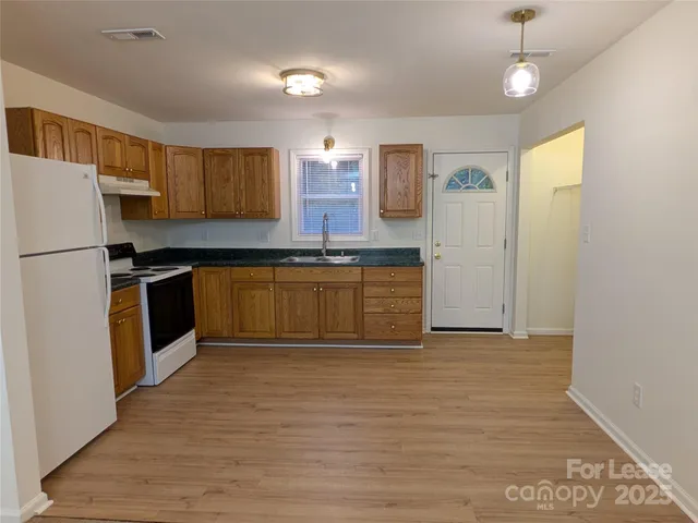 a kitchen with granite countertop a refrigerator a sink dishwasher a stove top oven a sink and dishwasher with wooden floor