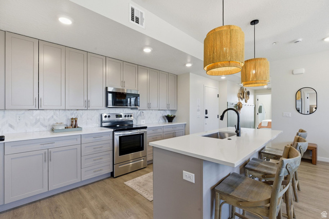 961 West Akoya Pearl Road, Unit 300 St. George, UT 84790 - Photo 16 of 60 Kitchen with gray cabinets, stainless steel appliances, light wood finished floors, and a center island with sink