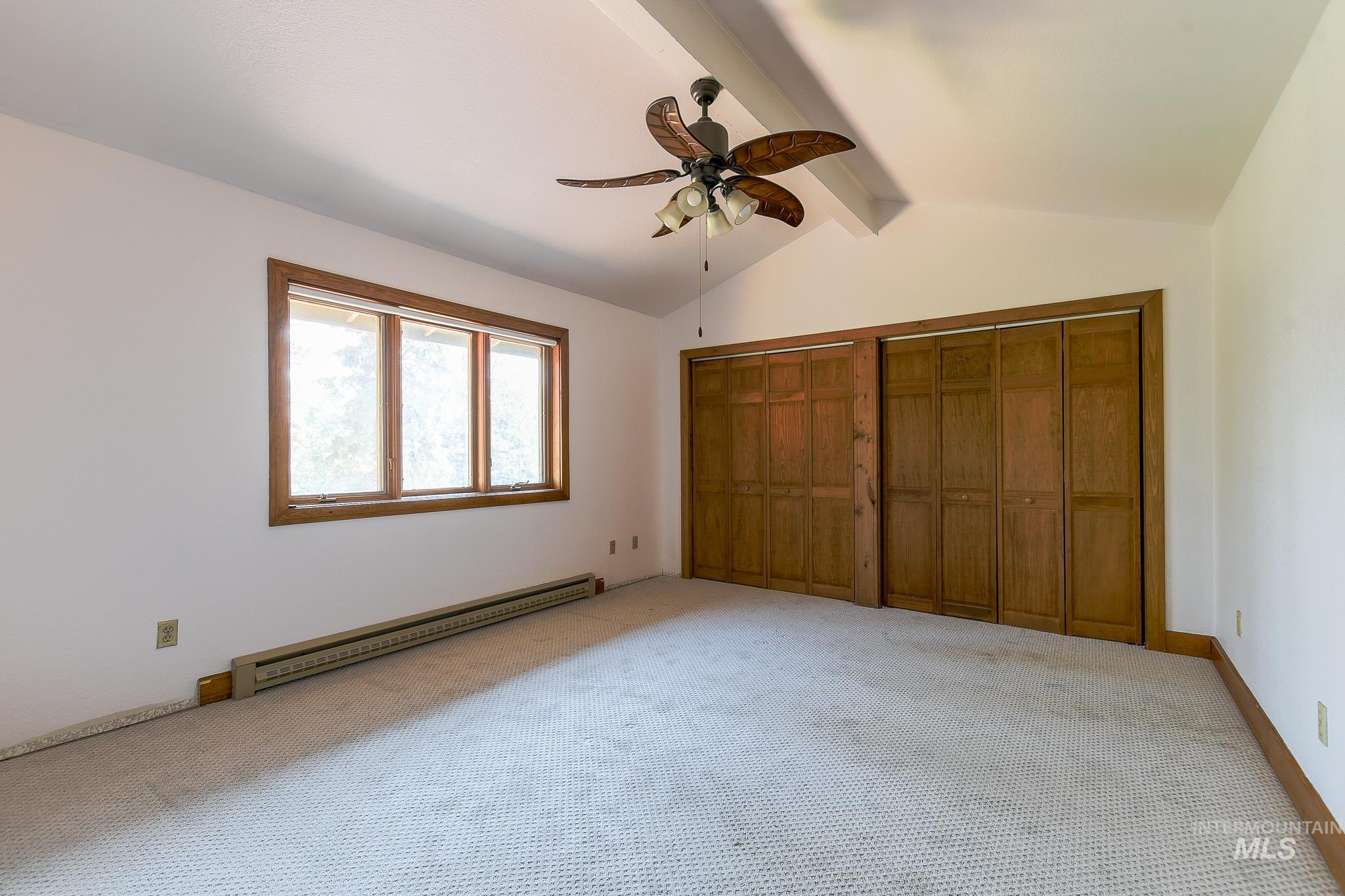 1045 Joyce Road Moscow, ID 83843 - Photo 21 of 50 Vaulted ceiling with exposed beam, ceiling fan with integrated lighting, wood-trim windows, and bi-fold closet doors