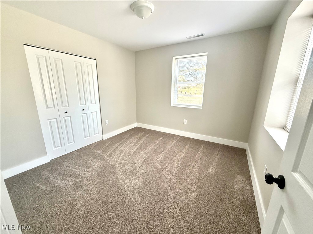 4670 Sandy Lake Road Ravenna, OH 44266 - Photo 17 of 26 Unfurnished bedroom featuring dark colored carpet, a closet, visible vents, and baseboards