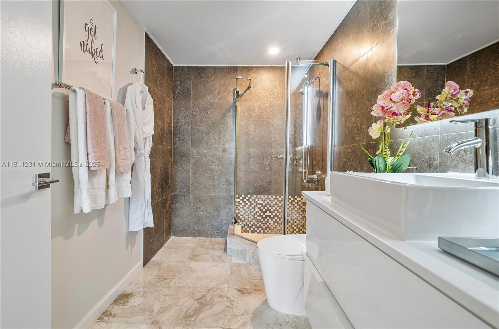 2889 McFarlane Road, Unit 1801 Miami, FL 33133 - Photo 35 of 38 a bathroom with a sink a toilet and shower