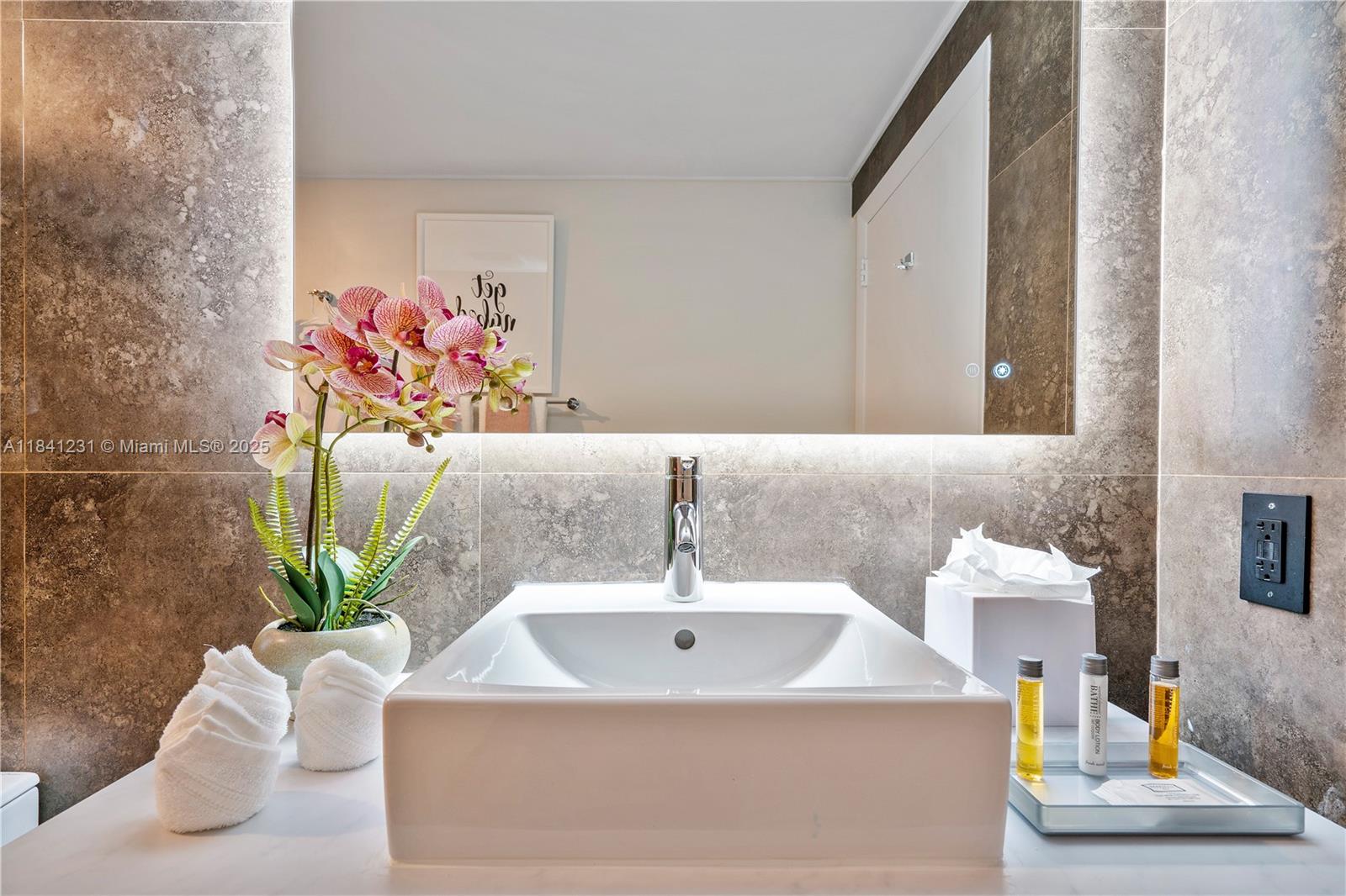 2889 McFarlane Road, Unit 1801 Miami, FL 33133 - Photo 36 of 38 a bathroom with a sink a mirror and vanity