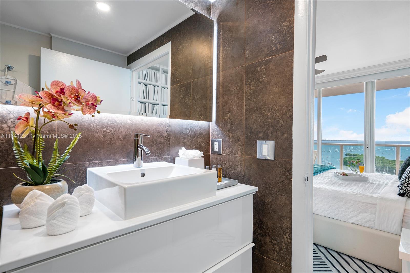 2889 McFarlane Road, Unit 1801 Miami, FL 33133 - Photo 38 of 38 a bathroom with a sink a mirror and a potted plant