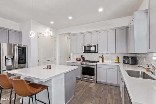 a kitchen with stainless steel appliances kitchen island a sink table and chairs