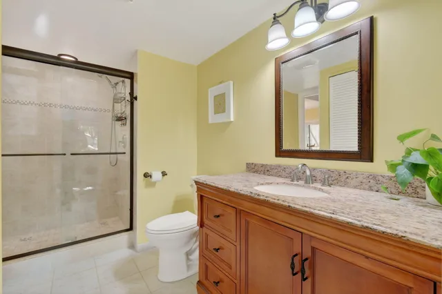a bathroom with a granite countertop sink a toilet and a mirror
