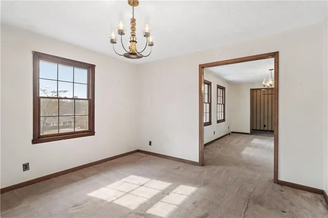 an empty room with chandelier fan and windows