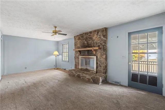an empty room with windows and fireplace