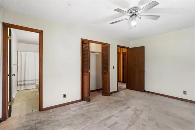 an empty room with closet and a ceiling fan
