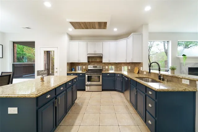 a large kitchen with stainless steel appliances granite countertop a sink counter space cabinets and a large window