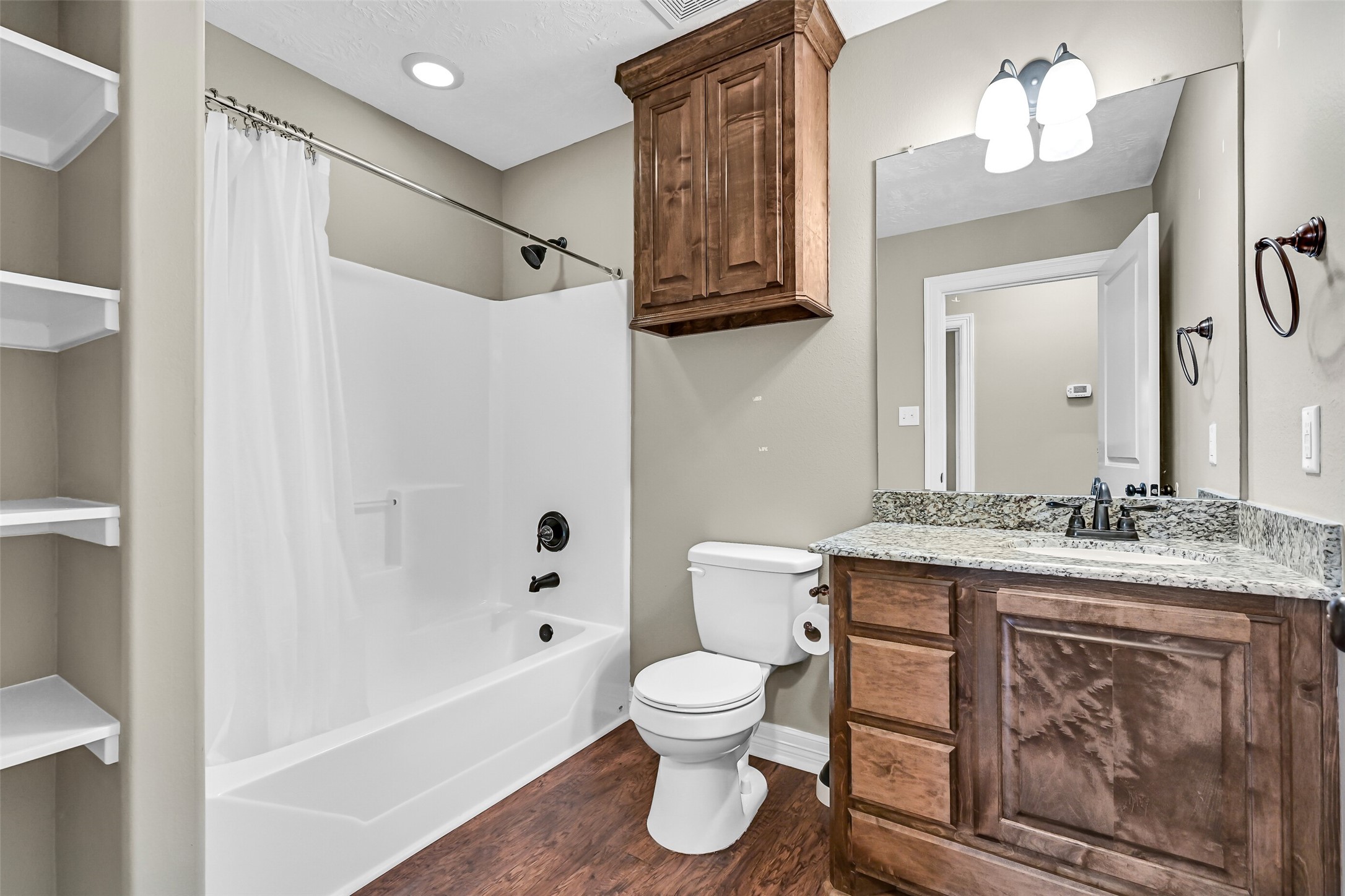 11930 Bastrop Beach Road Angleton, TX 77515 - Photo 26 of 29 Conveniently located between the secondary bedrooms, the hall bath features granite countertops, custom cabinetry, a tub/shower combination, and built-in linen shelving for added everyday storage.