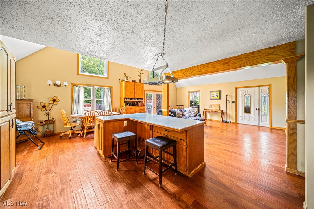 5050 Middle Road Conneaut, OH 44030 - Photo 18 of 35 Kitchen featuring a center island, light wood-style floors, a textured ceiling, lofted ceiling, and pendant lighting