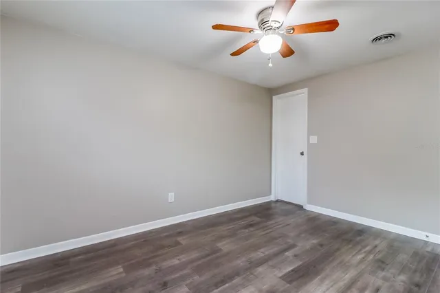 a view of an empty room with window and a ceiling fan