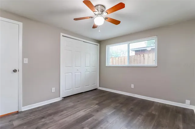an empty room with wooden floor ceiling fan and windows