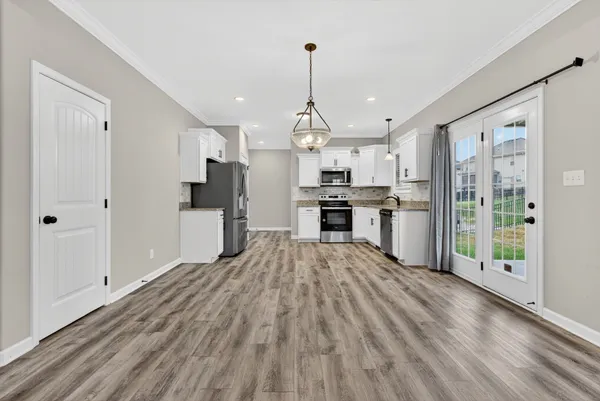a open kitchen with stainless steel appliances granite countertop a refrigerator oven stove a sink dishwasher and white cabinets with wooden floor