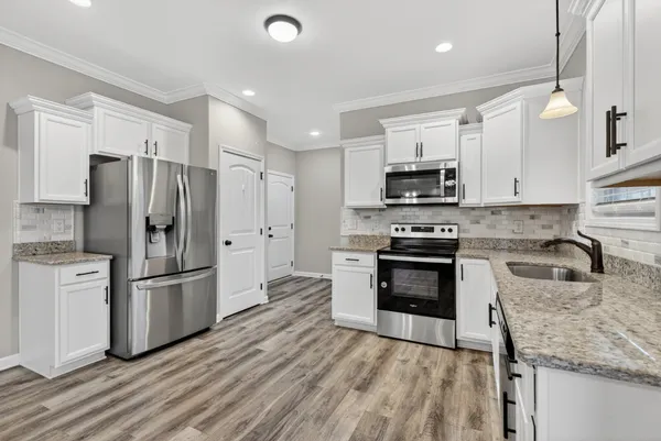 a kitchen with granite countertop a refrigerator stove and microwave
