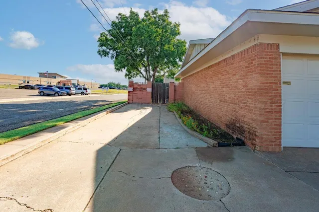 a view of a backyard with plants and cars parked