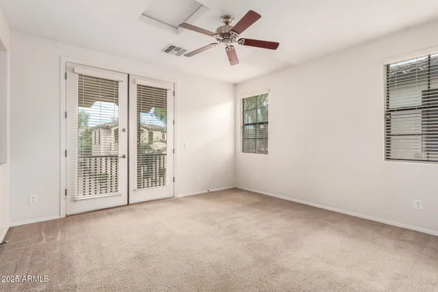 an empty room with chandelier fan and windows
