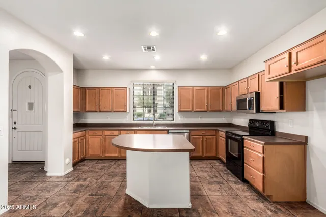 a kitchen with stainless steel appliances granite countertop a sink a stove top oven a counter space and cabinets