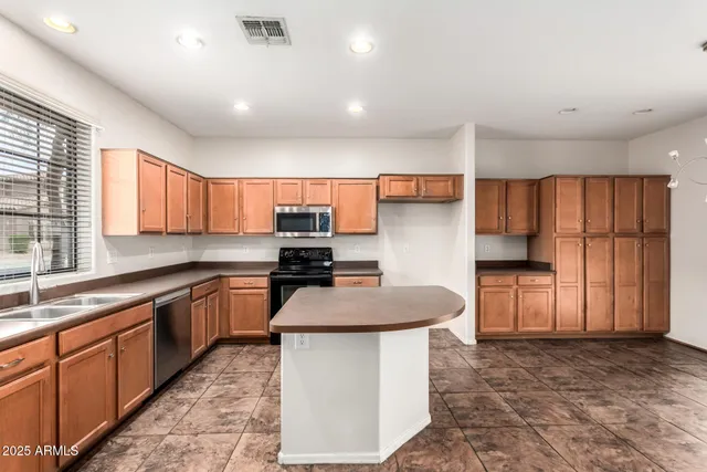 a kitchen with stainless steel appliances kitchen island granite countertop a stove a sink and a refrigerator