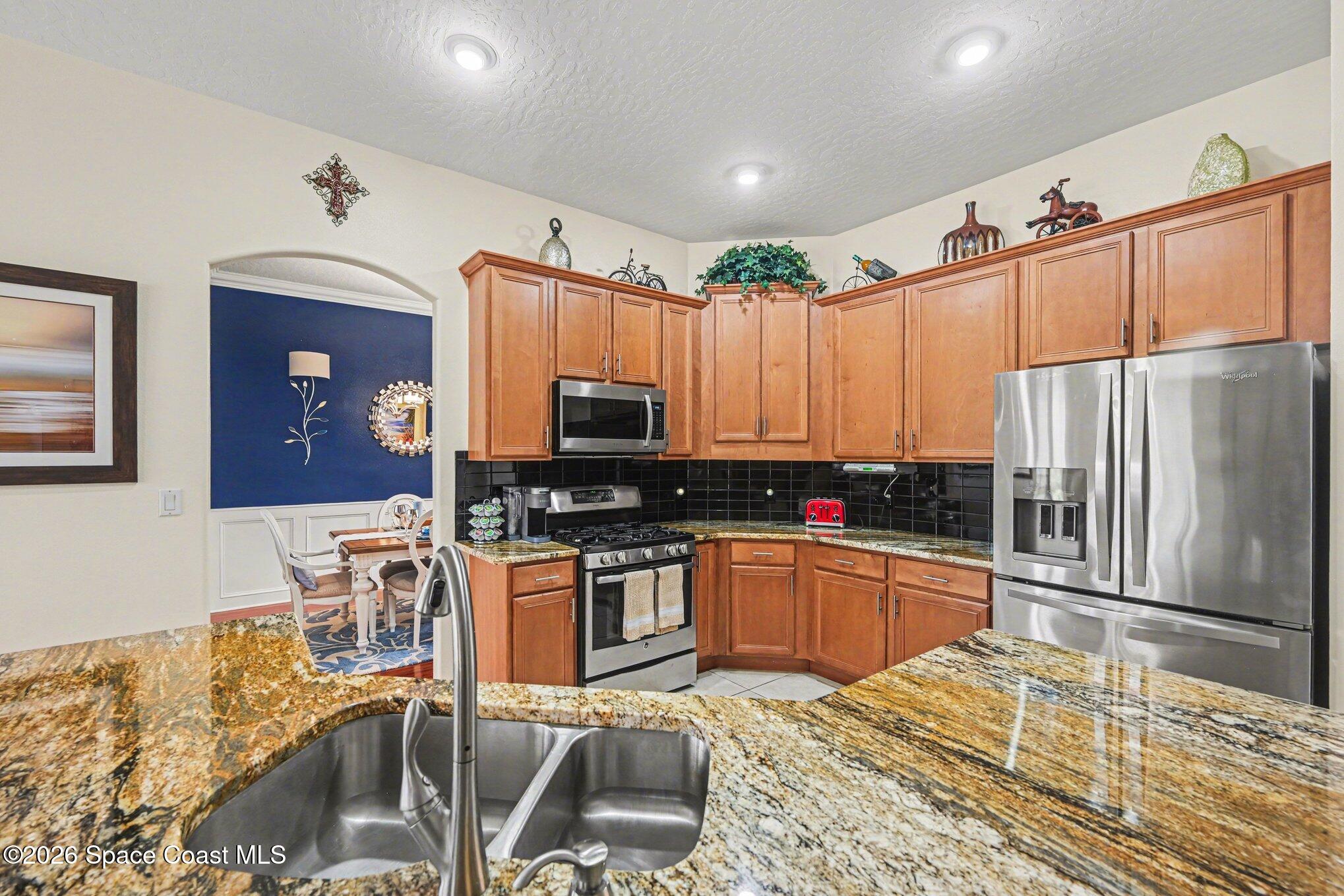 3760 Fringetree Lane Melbourne, FL 32940 - Photo 13 of 36 a kitchen with stainless steel appliances granite countertop a sink refrigerator and cabinets