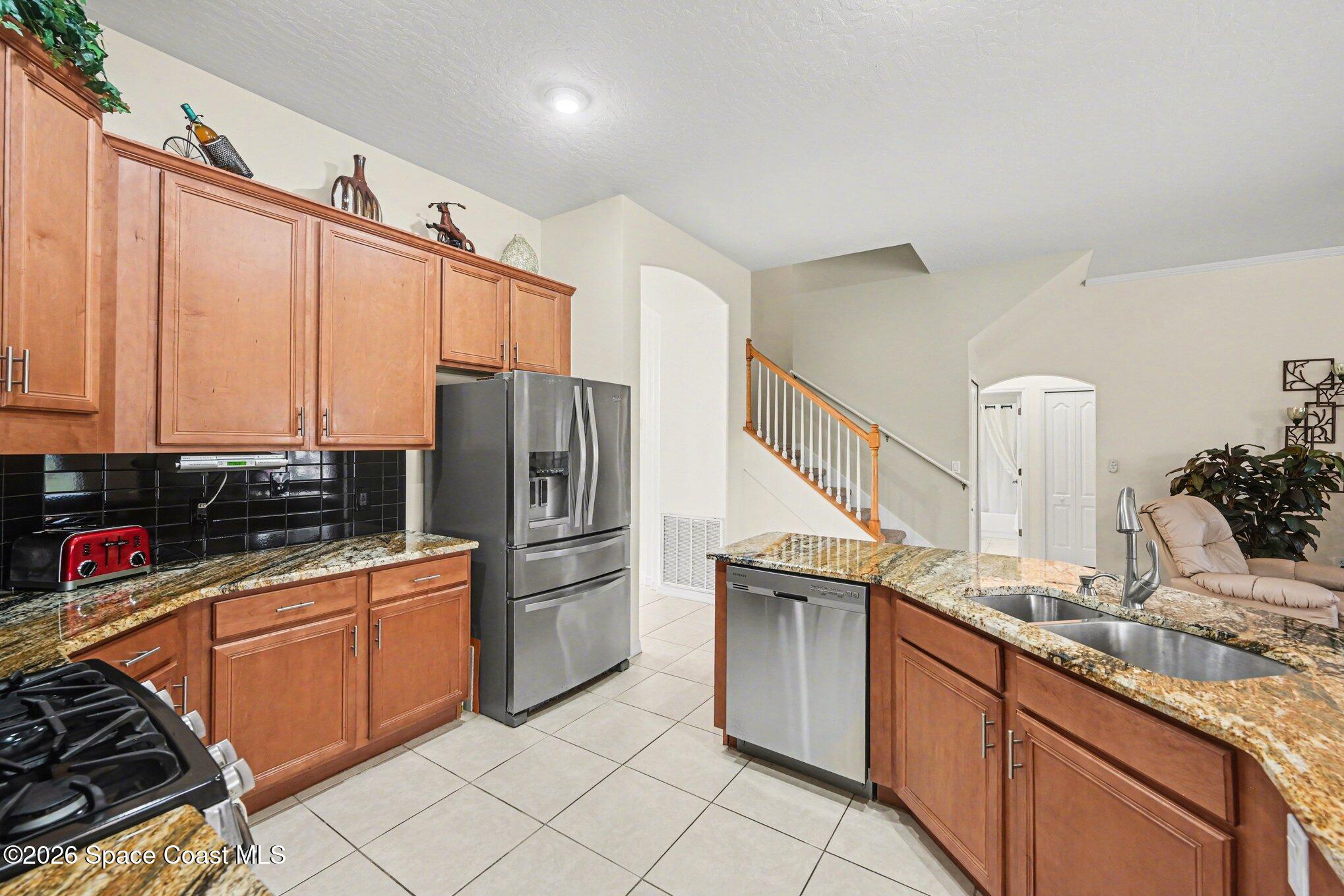 3760 Fringetree Lane Melbourne, FL 32940 - Photo 14 of 36 a kitchen with stainless steel appliances granite countertop a sink stove and refrigerator