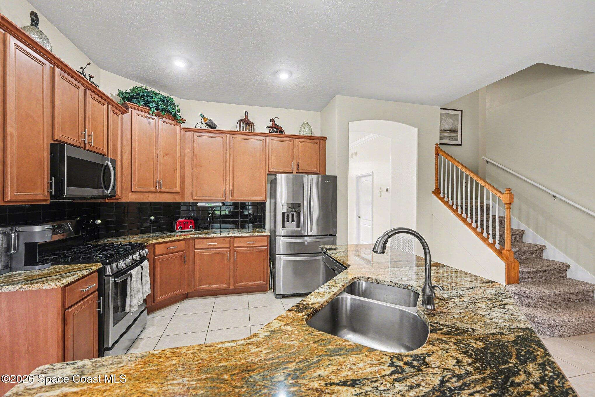3760 Fringetree Lane Melbourne, FL 32940 - Photo 16 of 36 a kitchen with stainless steel appliances granite countertop a sink stove and refrigerator
