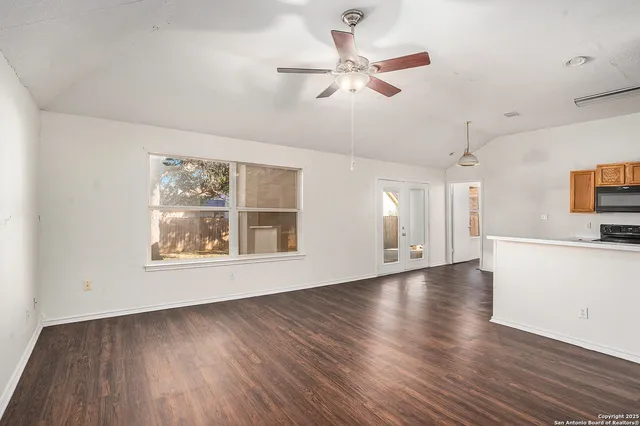 a view of an empty room with a window and wooden floor