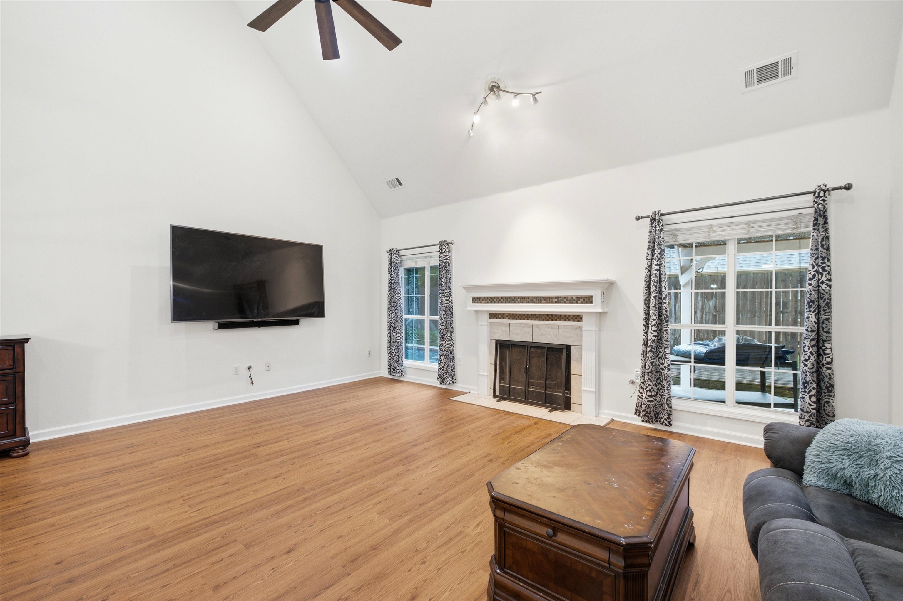 96 Berryfield Cove Collierville, TN 38017 - Photo 9 of 39 Spacious living area featuring a vaulted ceiling with a ceiling fan, wood-finish flooring, and a fireplace with a decorative mantel and hearth
