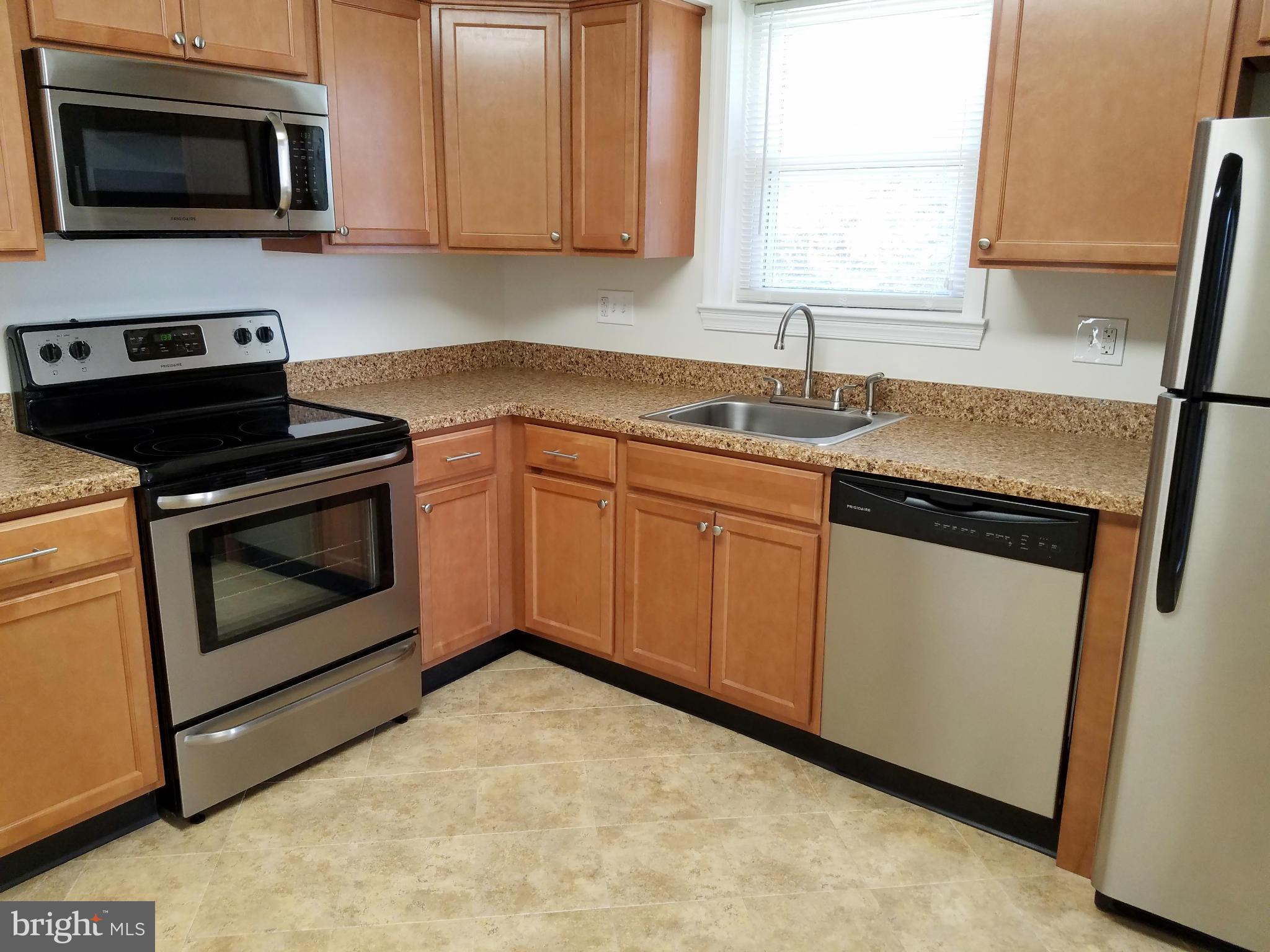 12908 Glynis Road Clinton, MD 20735 - Photo 14 of 30 a kitchen with stainless steel appliances granite countertop a sink a stove a microwave and wooden cabinets