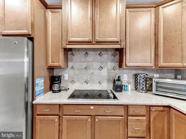 a kitchen with stainless steel appliances granite countertop a refrigerator a sink dishwasher a stove and a dining table with wooden floor