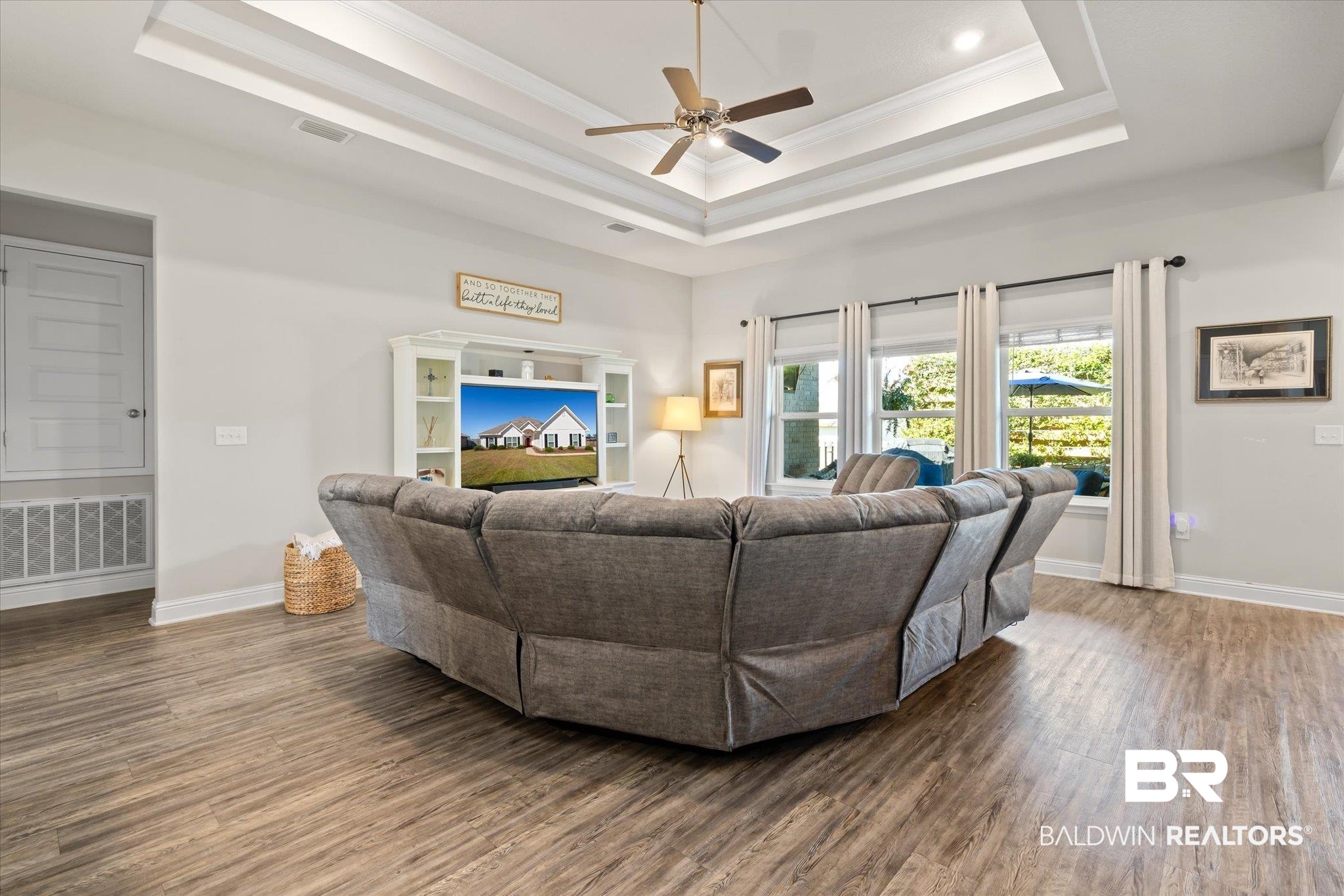 12899 Sanderling Loop Daphne, AL 36527 - Photo 7 of 28 Living room featuring ceiling fan, a tray ceiling, ornamental molding, and dark hardwood / wood-style flooring
