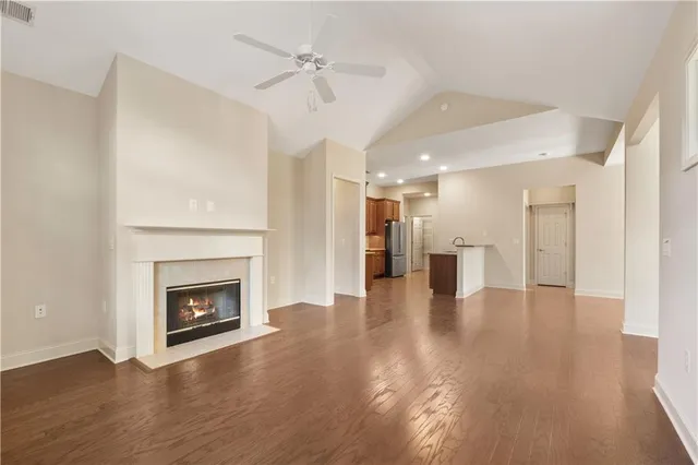 a view of a livingroom with a fireplace a ceiling fan and windows