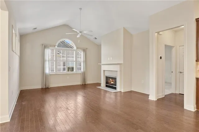 an empty room with wooden floor a fireplace and windows