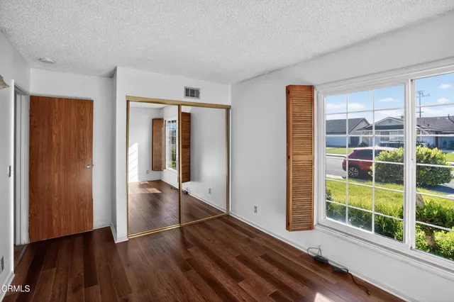 an empty room with wooden floor and windows