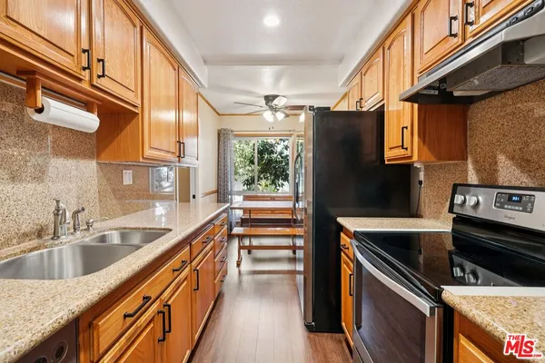 a kitchen with stainless steel appliances granite countertop a sink a stove and a refrigerator