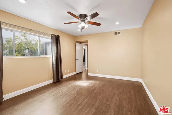 a view of an empty room with wooden floor and a window