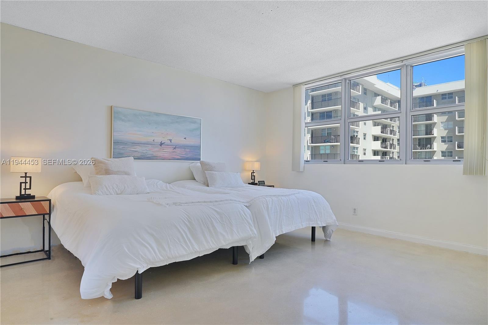 9225 Collins Avenue, Unit 705 Surfside, FL 33154 - Photo 9 of 17 a bedroom with a bed lamp and a large mirror