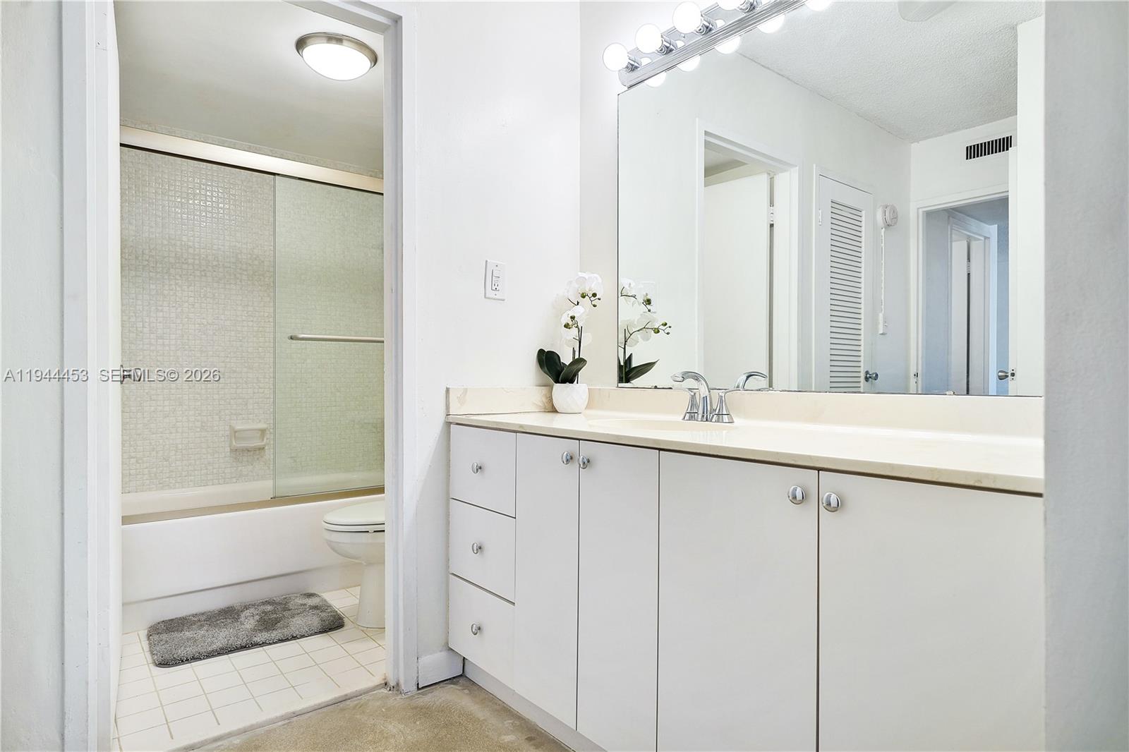 9225 Collins Avenue, Unit 705 Surfside, FL 33154 - Photo 10 of 17 a bathroom with a shower sink vanity and mirror