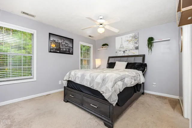 a bed sitting in a spacious bedroom next to a window
