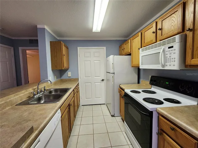 a kitchen that has a sink a stove and a refrigerator