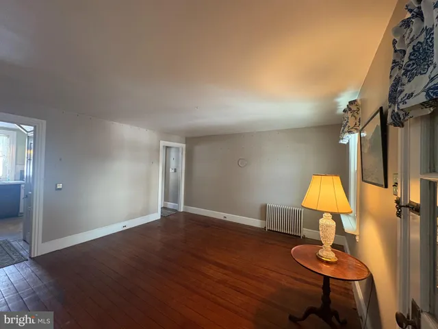 a view of a room with wooden floor table lamp and window