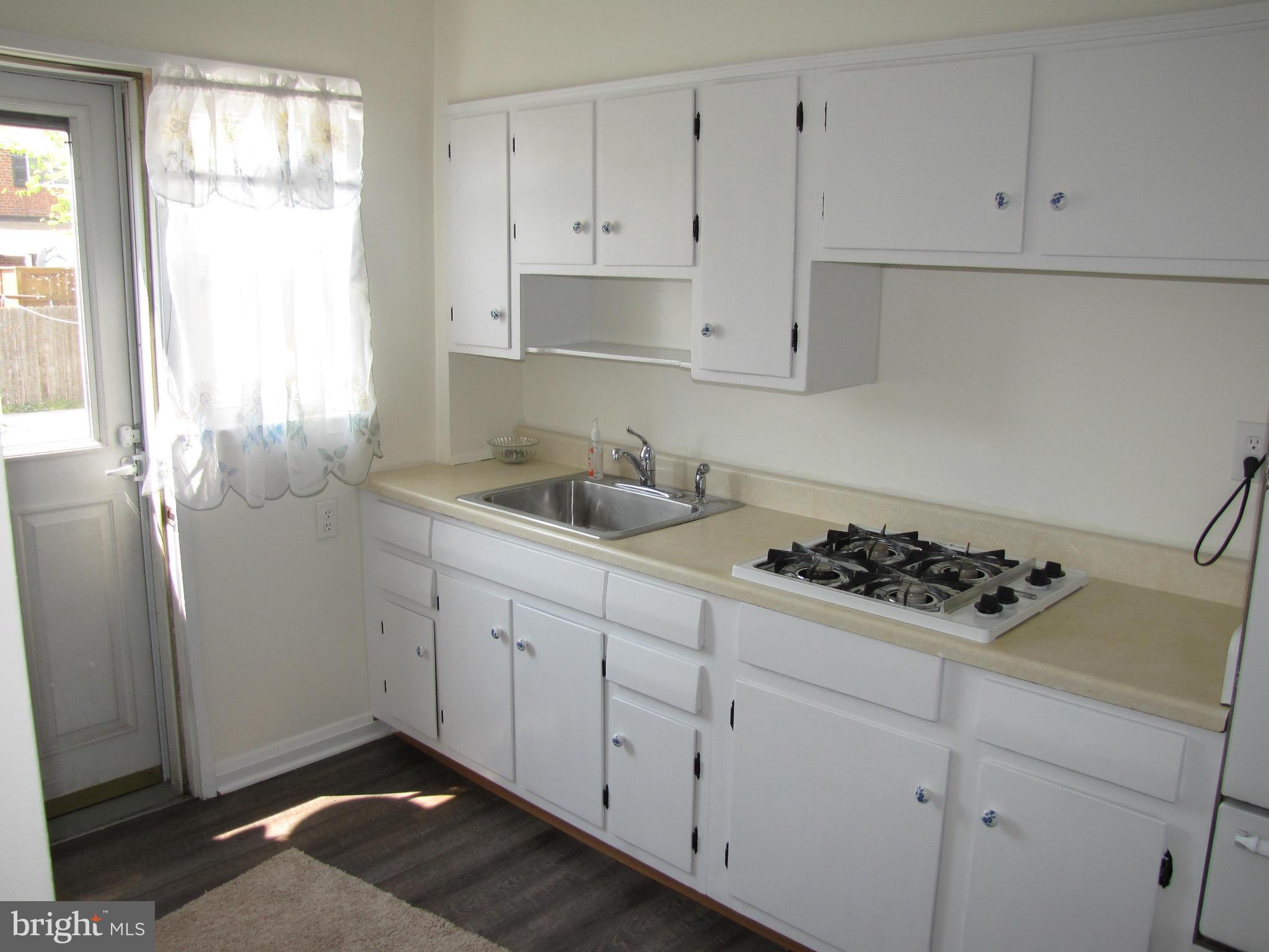 7900 Charlesmont Road Baltimore, MD 21222 - Photo 7 of 18 a kitchen with white cabinets and a stove a window