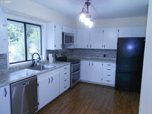 5355 Southwest River Road Hillsboro, OR 97123 - Photo 20 of 24 a kitchen with granite countertop a stove a sink a window and cabinets