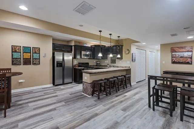 a kitchen with stainless steel appliances kitchen island granite countertop a table chairs and wooden floor