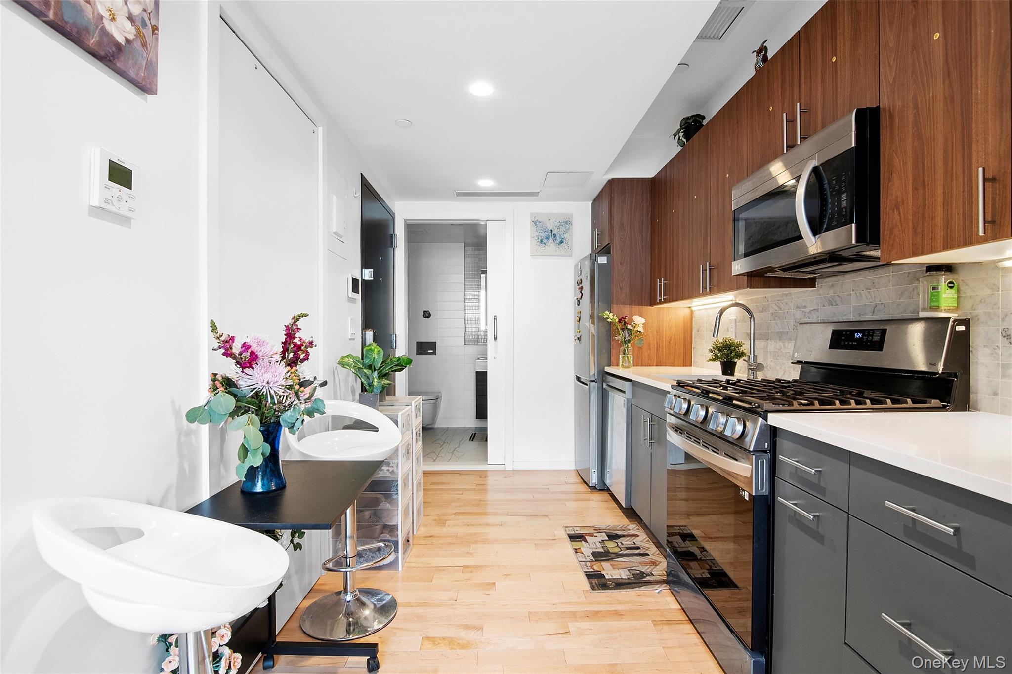 1064 Hancock Street, Unit 101 Brooklyn, NY 11221 - Photo 1 of 9 Modern kitchen featuring wood-finish upper cabinetry, gray lower cabinetry, and stainless steel appliances