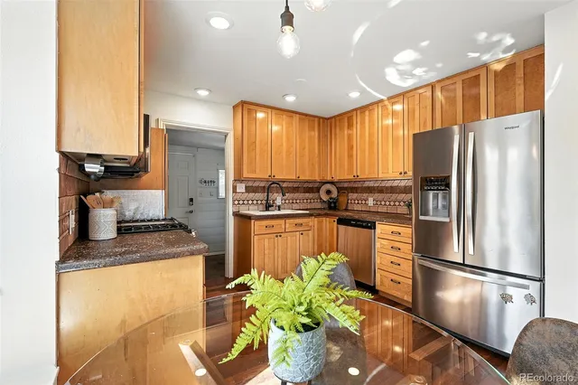 a kitchen with stainless steel appliances granite countertop a refrigerator a sink a stove and white cabinets