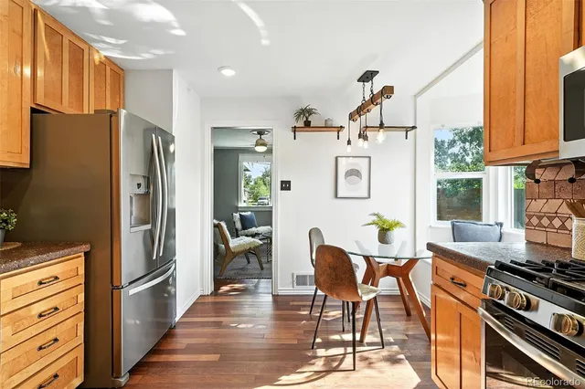 a kitchen with stainless steel appliances granite countertop a refrigerator and a stove top oven with wooden floor